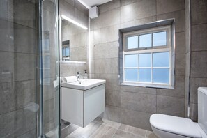 Une salle de bain moderne avec une douche à parois de verre, un lavabo blanc et des toilettes.