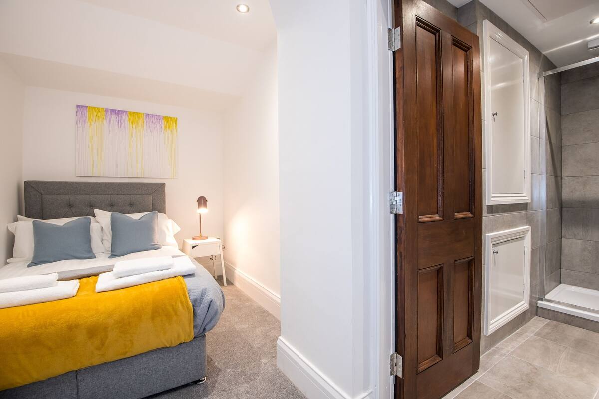 A bedroom with a bed, bedside table, and a wall-mounted artwork.