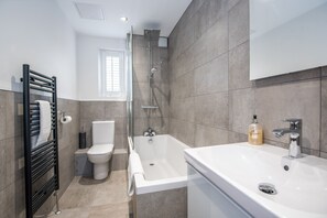 A modern bathroom with a bathtub, toilet, and a towel rack. - 52 Old Elvet (Durham)