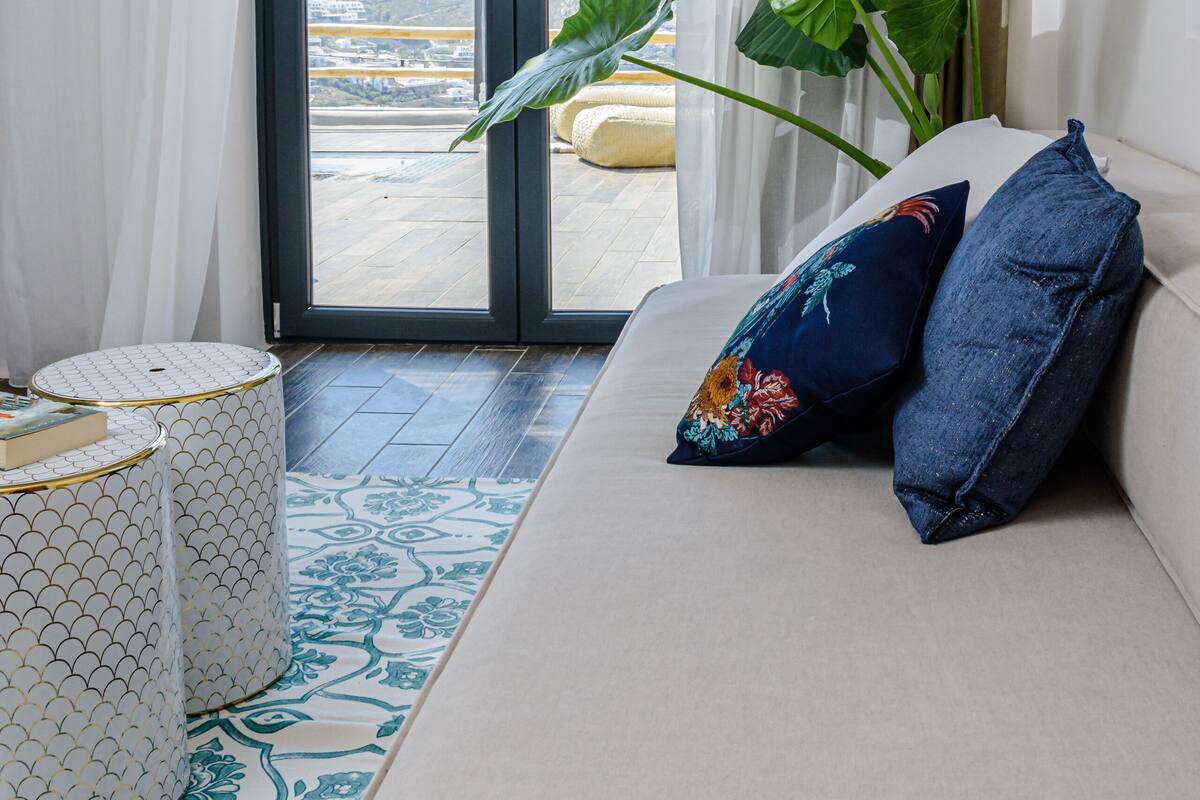 Una sala de estar moderna con un sofá, una mesita redonda y una planta grande.