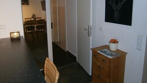 A room with a dining area, a wooden dresser with a vase, and a wall-mounted deer head artwork. - Wohnen im ehemaligen Kaminstudio (Lutherstadt Wittenberg)