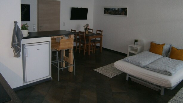 A compact room with a kitchenette, a dining area, and a bed. - Wohnen im ehemaligen Kaminstudio (Lutherstadt Wittenberg)