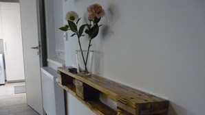 Una estantería de madera con un jarrón de vidrio que contiene flores sobre un fondo blanco.