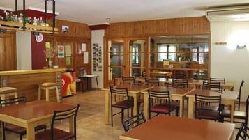 Un restaurant aux murs en bois, avec un espace bar. Des tables et des chaises sont disposées pour accueillir les clients.