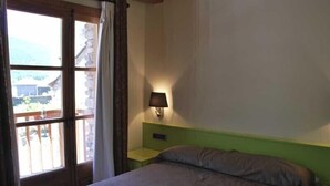 Un dormitorio con una cama, una mesita de noche, una lámpara y una ventana con cortinas.