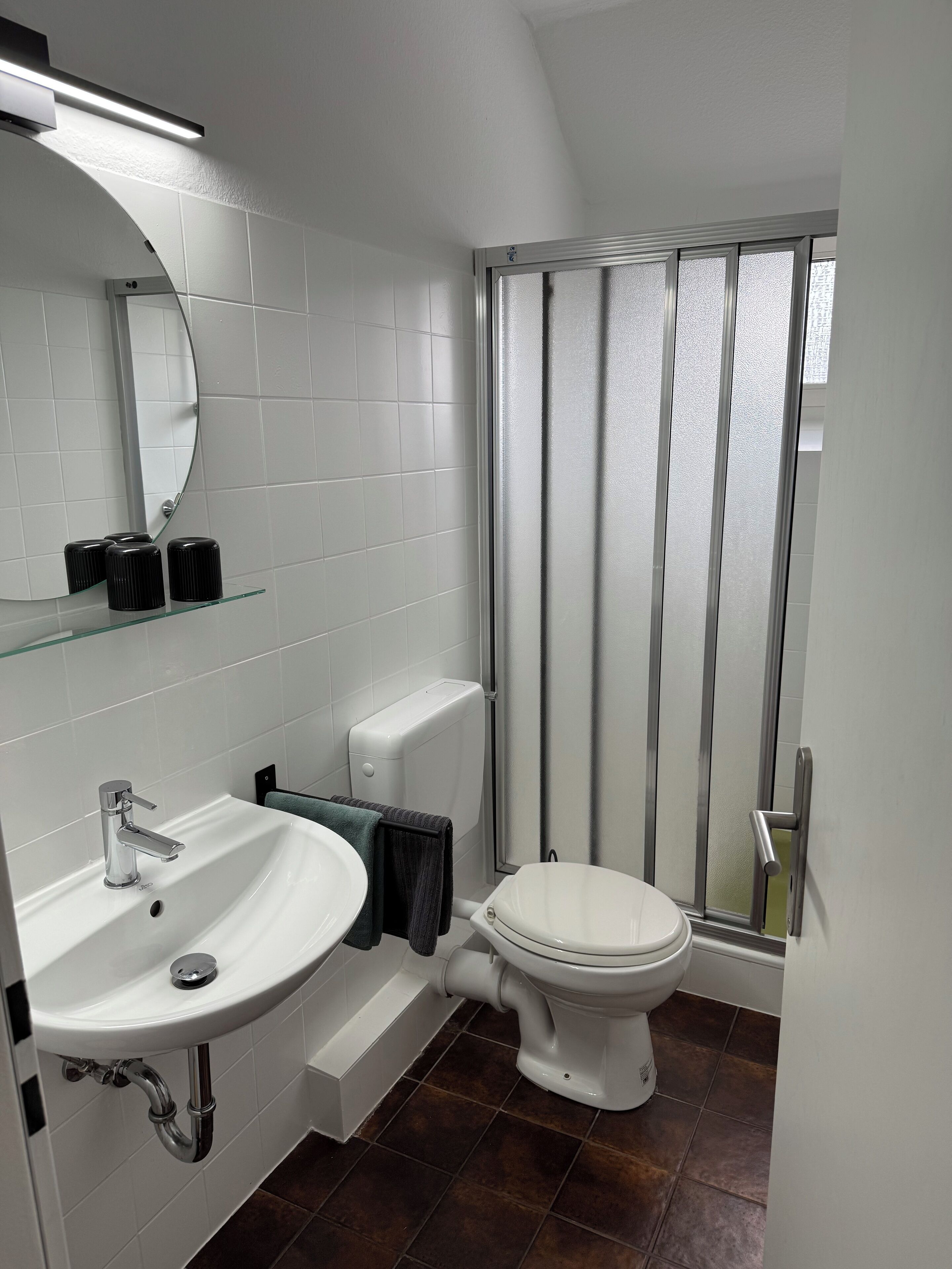 Un baño moderno con un lavabo, espejo y váter blancos.