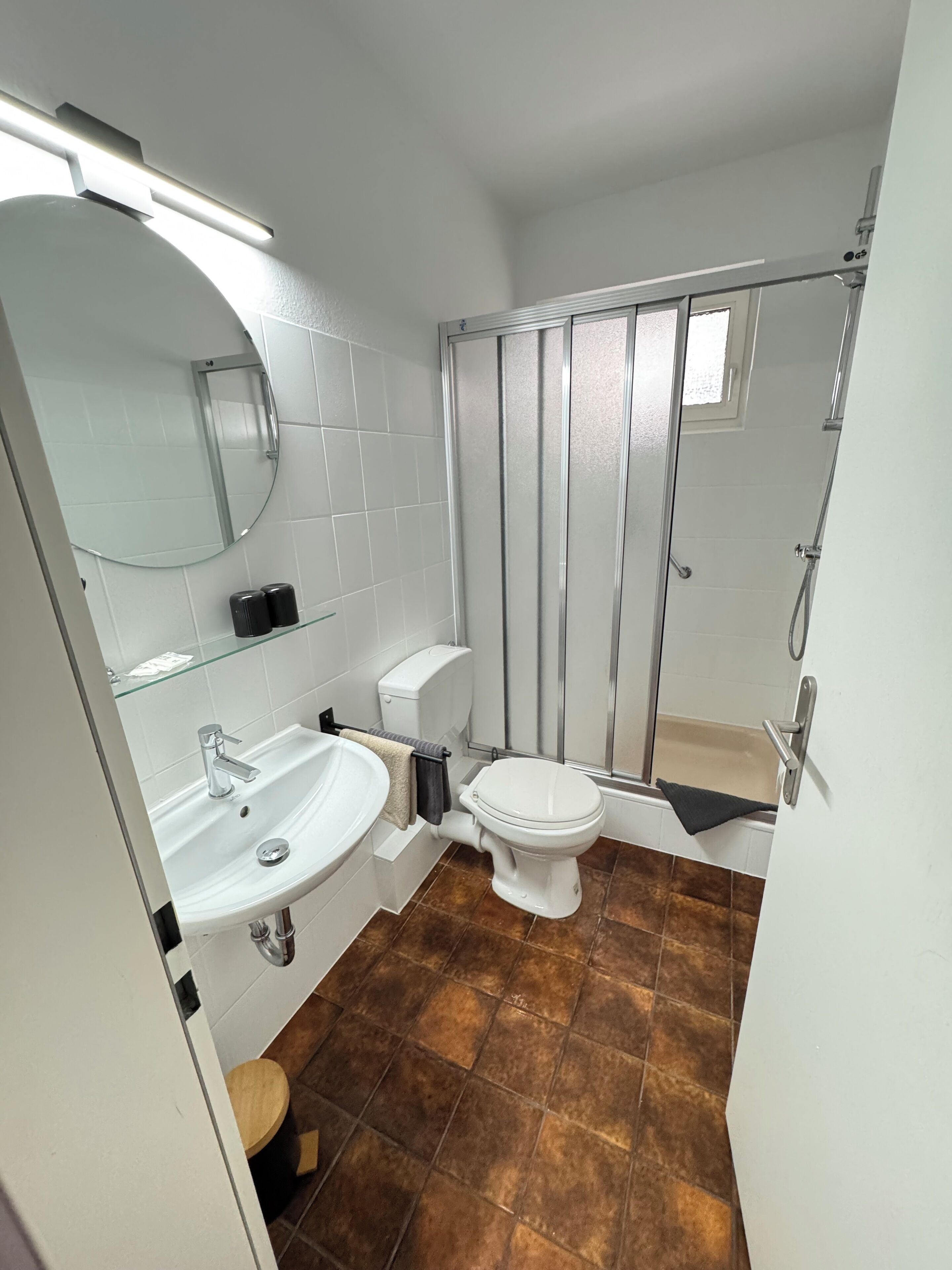 A modern bathroom with a white sink, toilet, and shower.