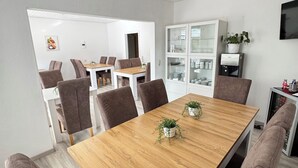 A modern dining area with a wooden table, brown upholstered chairs, and potted plants. - Hotel Pension Petra (Bad Zwischenahn)