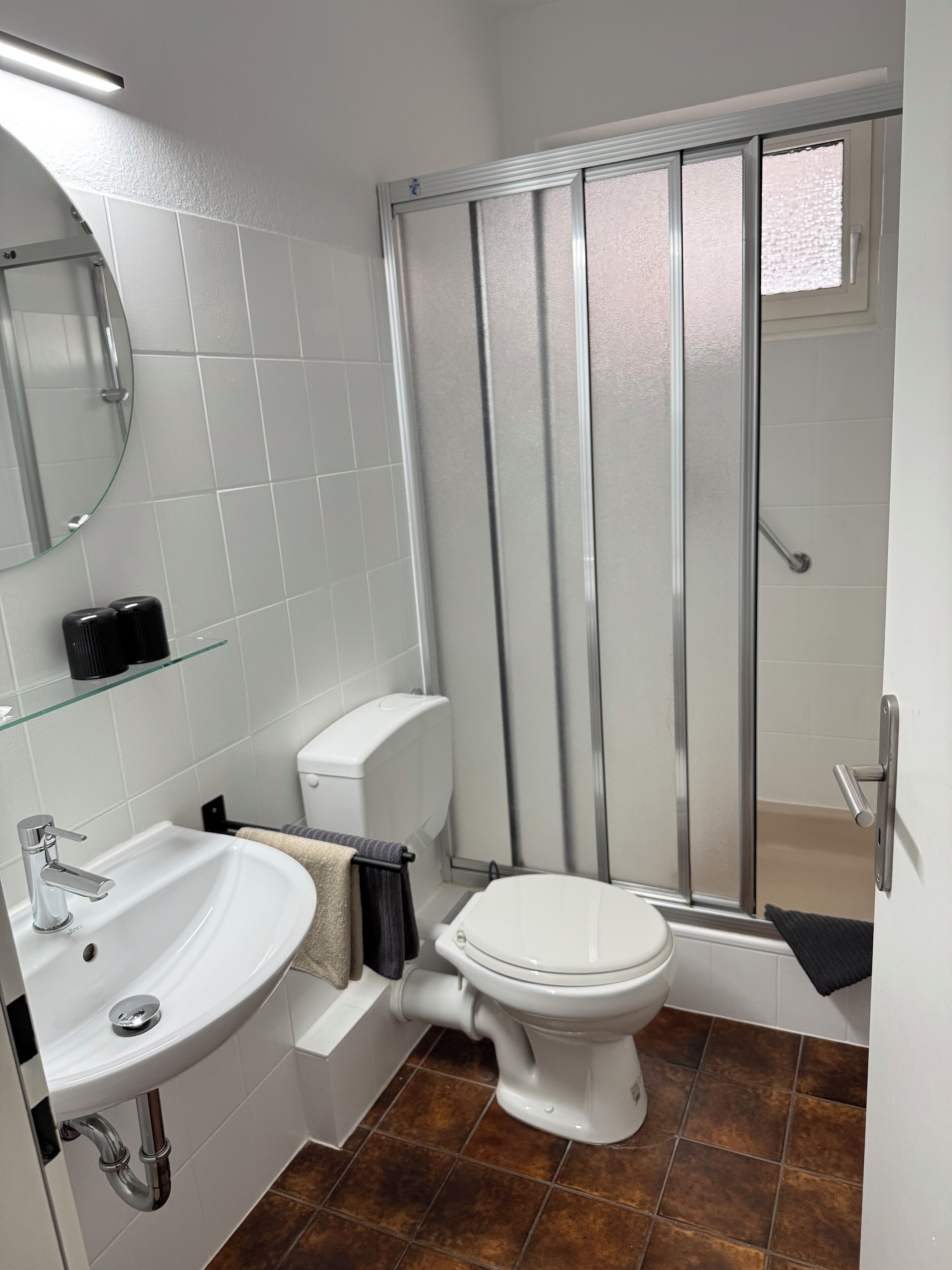Ein Badezimmer mit weißem Waschbecken, WC und Duschkabine.