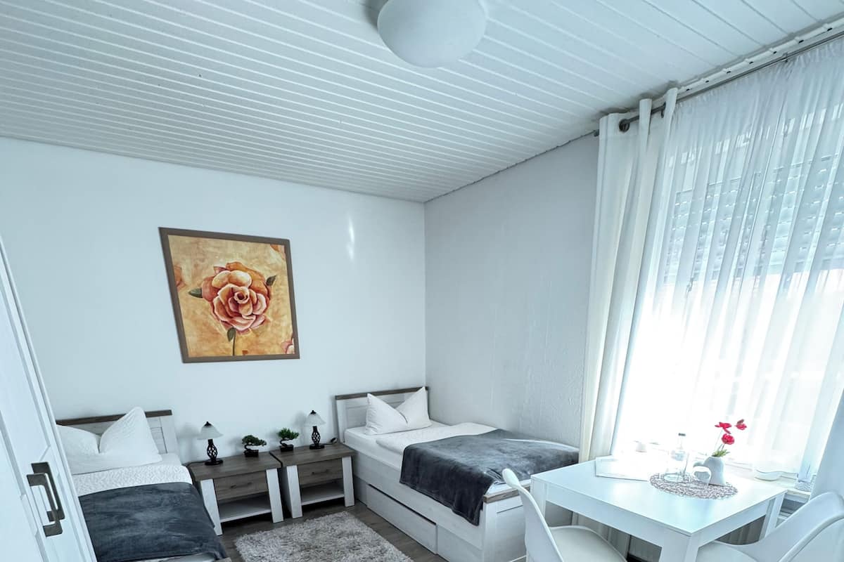 A compact, modern bedroom with a bed, bedside table, and a desk with a chair.