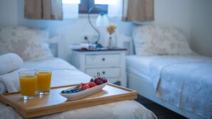 A neatly made bed with white bedding, a bedside table with a lamp, and a tray with fruit and juice. - Traditional holiday house in peaceful location, village Rakalj (Rakalj)