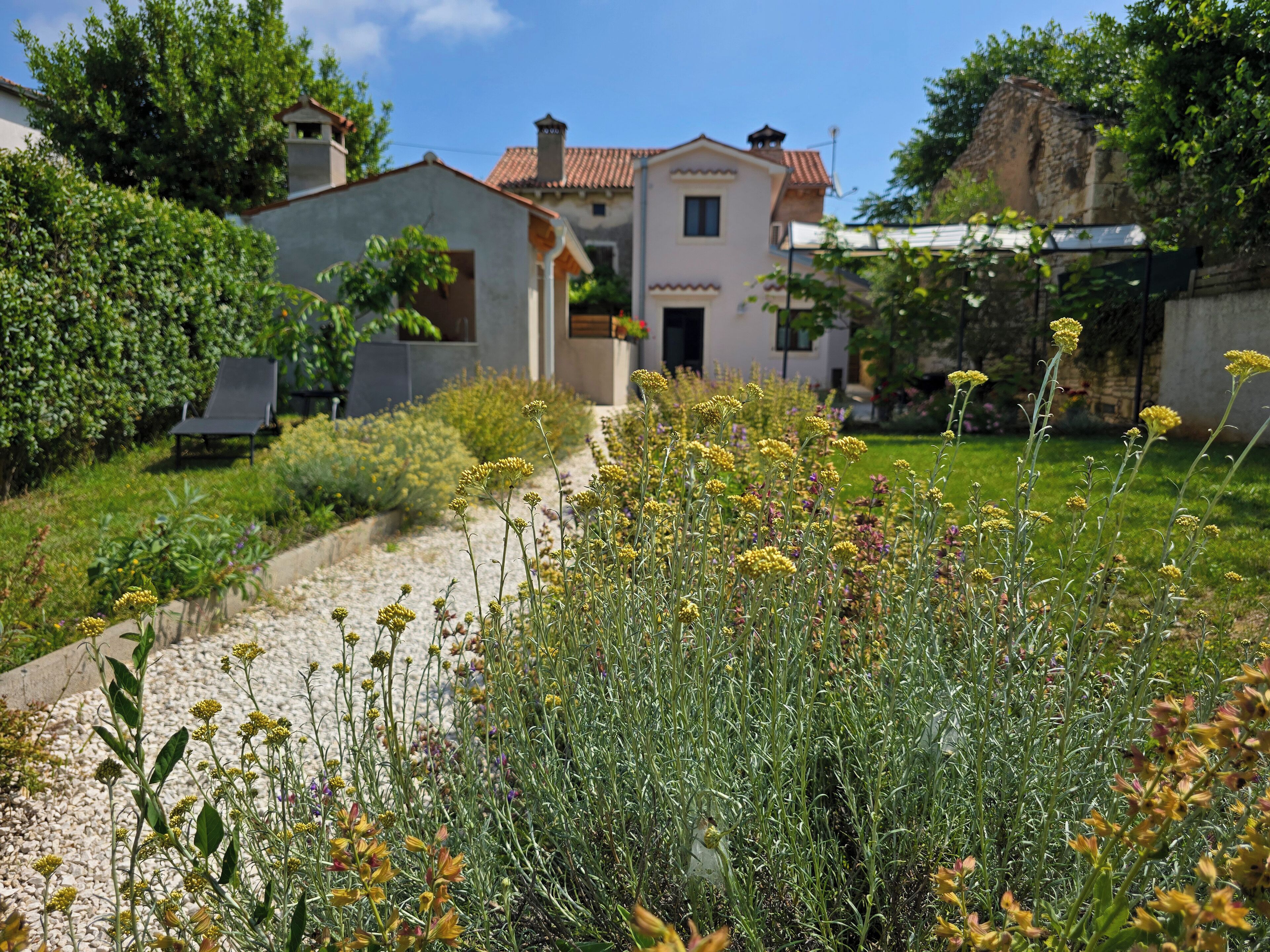 Une maison avec un jardin et un chemin qui mène à un bâtiment doté d’un balcon.