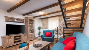 A living room with a TV, wooden furniture, a blue sofa, and a staircase. - Traditional holiday house in peaceful location, village Rakalj (Rakalj)