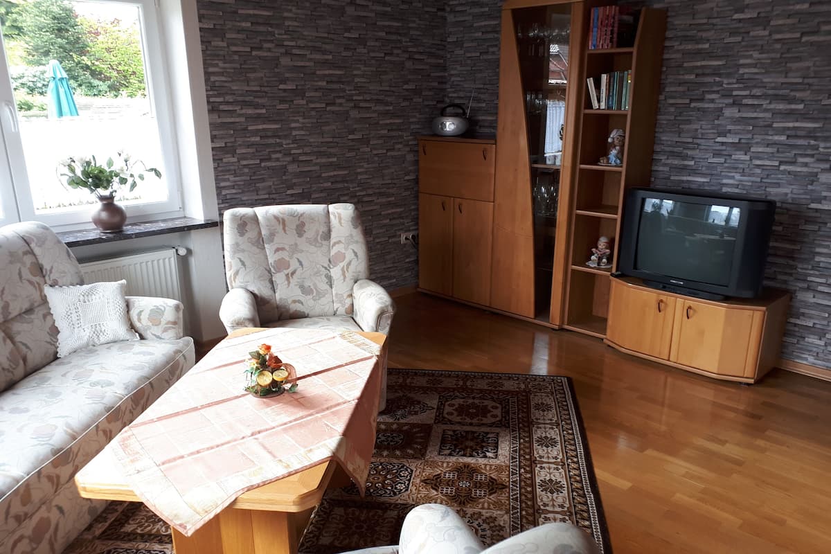 A living room with a sofa, armchairs, a coffee table, a television, and a bookshelf.