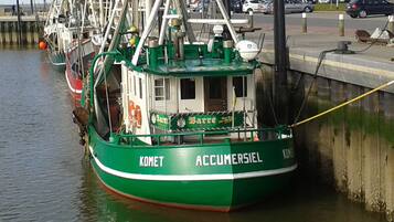 Un bote de pesca verde llamado 'KOMET ACCUMERSIEL' atracado en un muelle.
