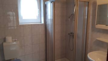 Une petite salle de bain avec une douche, des toilettes et un lavabo.