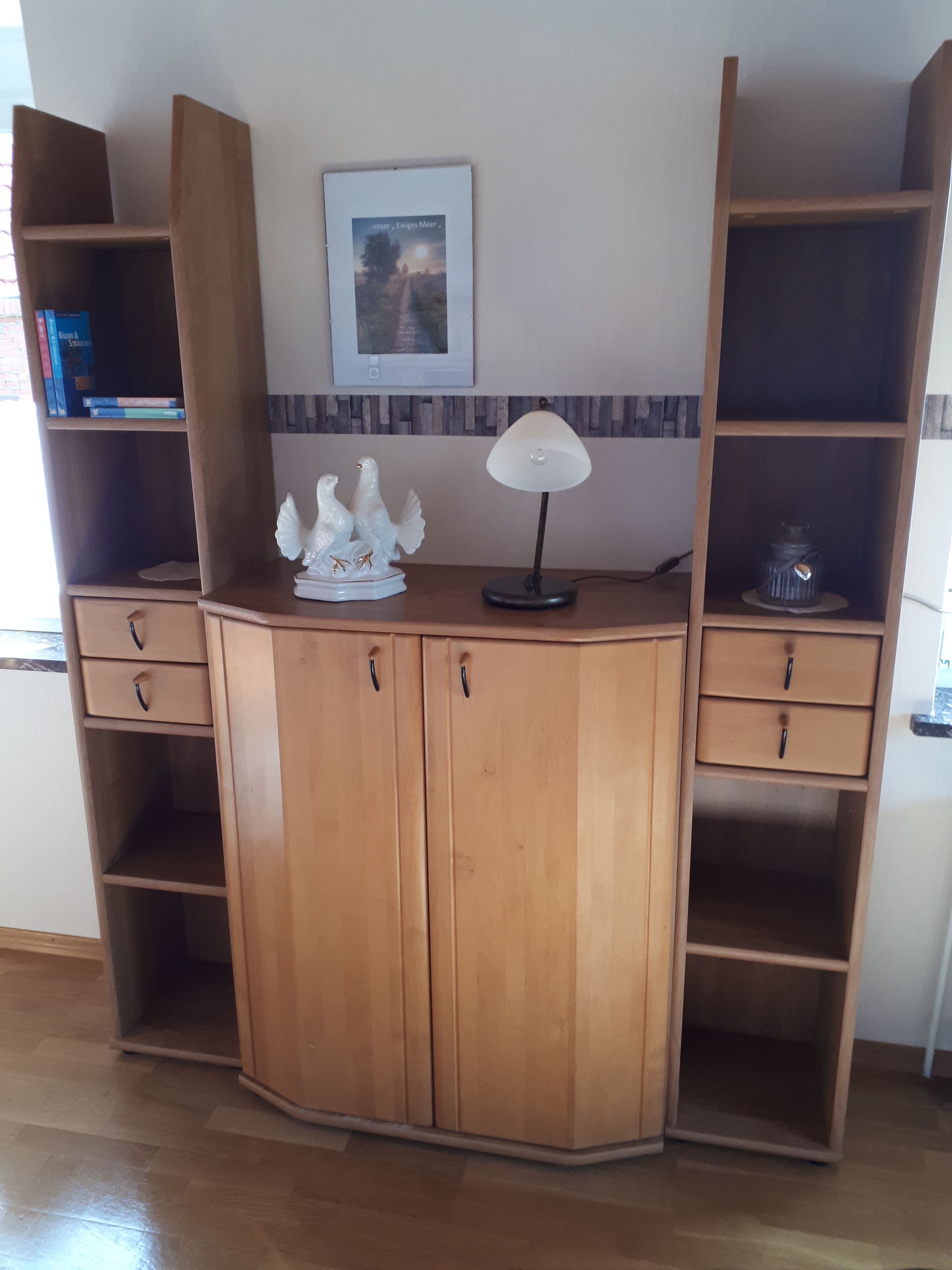 A corner desk with open shelves, a framed picture on the wall, and a decorative bird sculpture.