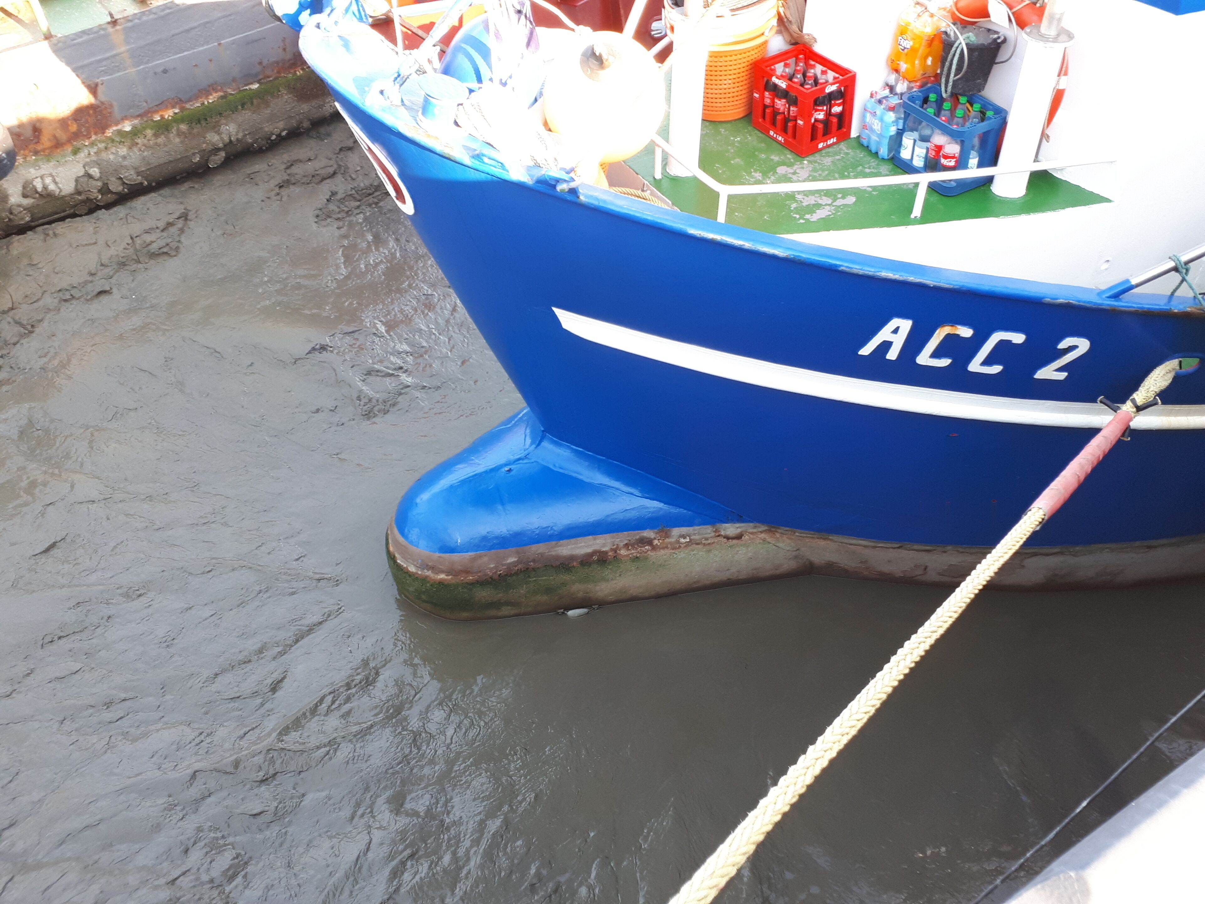 A blue boat with the registration number ACC 2 docked in a harbor.