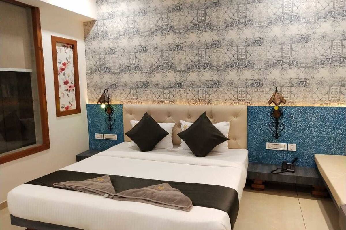 A hotel room with a large bed, two bedside tables, and a patterned wall.