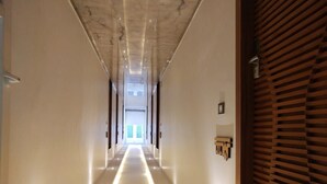 Un pasillo largo y estrecho con piso reflectante y una puerta de madera a la derecha.