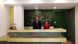 Mostrador de recepción con pared verde y un diseño decorativo de hojas.