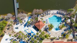 Luchtbeeld van een resort met een groot zwembad, ligbedden en palmbomen.