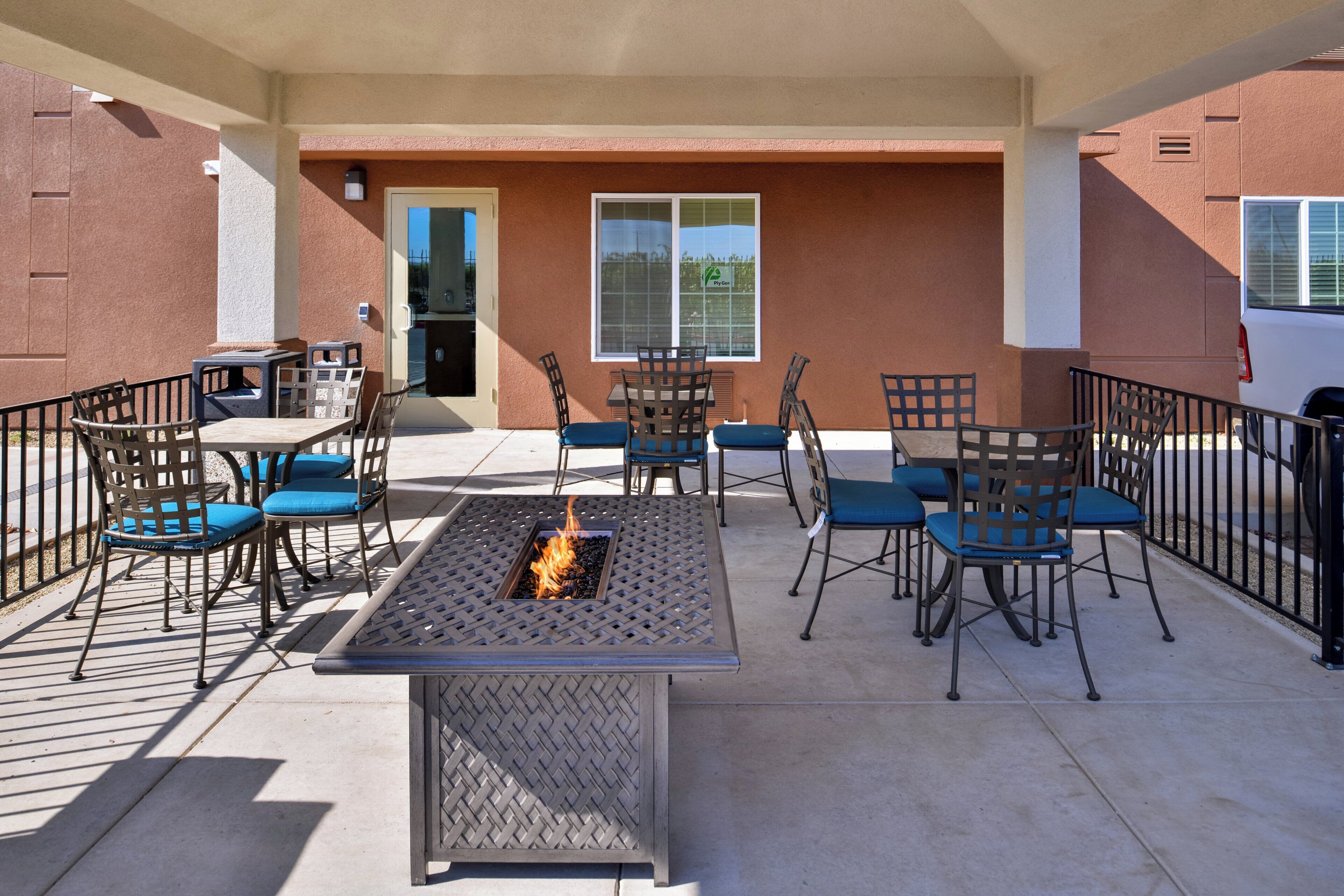 Un área de patio al aire libre con una chimenea, asientos y vistas del edificio.