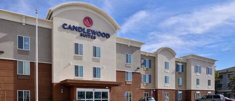 A hotel with a modern facade, a prominent entrance, and a parking lot with several cars.