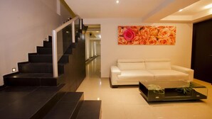 A modern living room with a staircase, a white sofa, and a glass coffee table. - Mar Bohemio (Isla Mujeres)