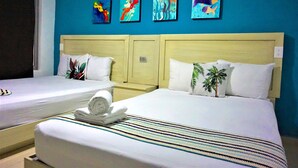 A hotel room with two beds, a blue wall, and four colorful paintings. - Mar Bohemio (Isla Mujeres)