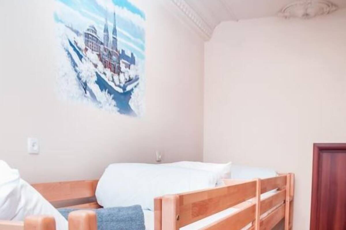 A room with three bunk beds, a white wall, and a painting of a cityscape.