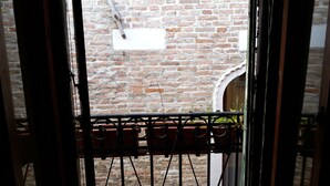A view through a metal gate with a brick wall in the background.