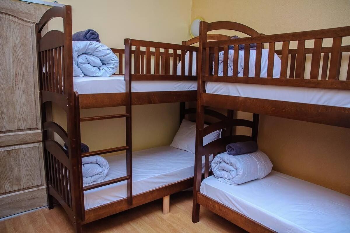 A bunk bed room with wooden frames and white bedding.
