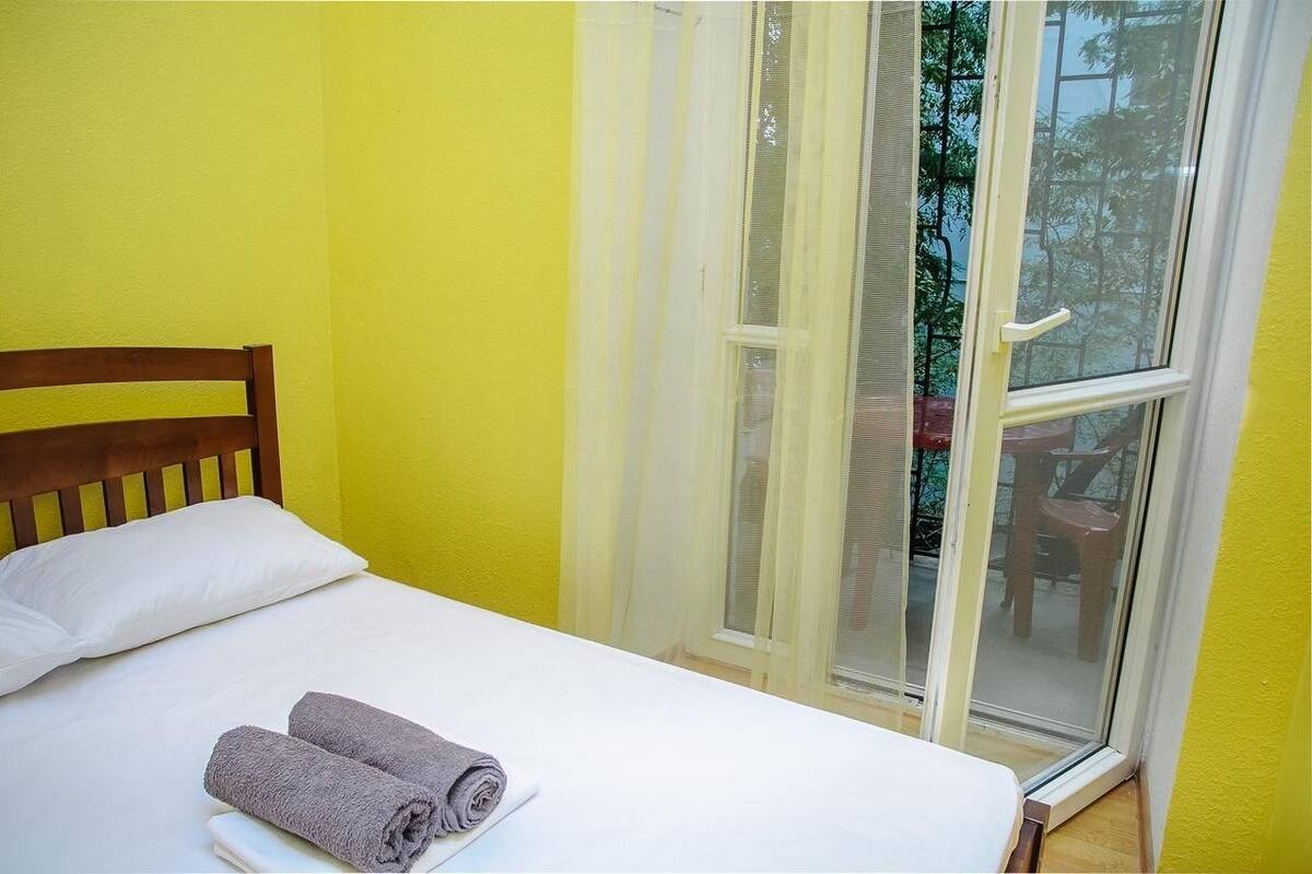A bed with white linens, a wooden headboard, and two rolled towels.