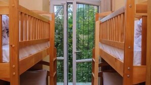 A room with bunk beds, a large arched window, and a view of greenery outside. - Golden Globus Hostel (Kyiv)