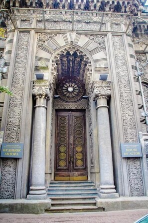A building with ornate architectural details, including a large wooden door with intricate patterns and two columns on either side. - Golden Globus Hostel (Kyiv)