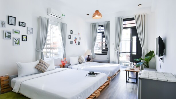 Habitación de hotel con dos camas, televisión, escritorio y ventana con cortinas.