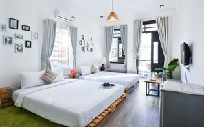 Ett hotellrum med två sängar, en TV, ett skrivbord och ett fönster med gardiner.