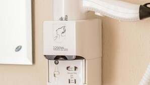 A wall-mounted hair dryer with a cord, a power outlet, and a switch. - Globus Lipki Hostel (Kyiv)