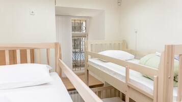 A room with bunk beds, a wardrobe, and a window with curtains.