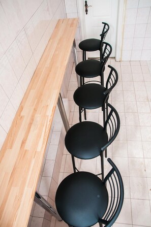 A kitchen with a wooden countertop and four black chairs with curved backs.