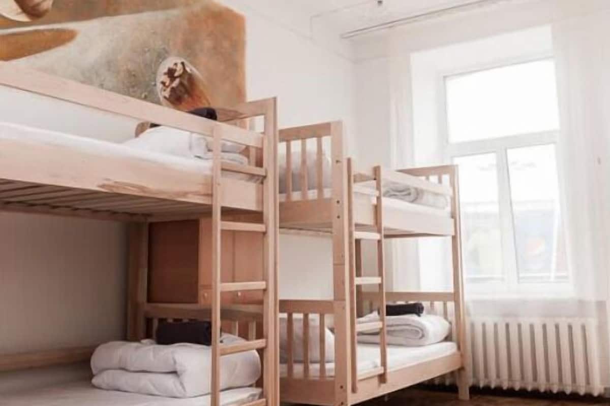 A room with two bunk beds, a radiator, and a window with curtains.