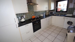 Una cocina compacta con armarios blancos, estufa, microondas y lavadora.