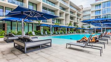 Alberca al aire libre, sombrillas en la alberca y camastros