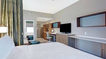 Une chambre d’hôtel avec un grand lit, un bureau avec une chaise, une télévision et une salle de bain visible au fond.