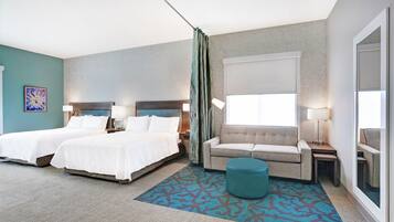 A hotel room with two beds, a sofa, a small ottoman, and a large window.