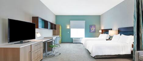 A hotel room with a bed, a desk with a TV, a chair, and a window.