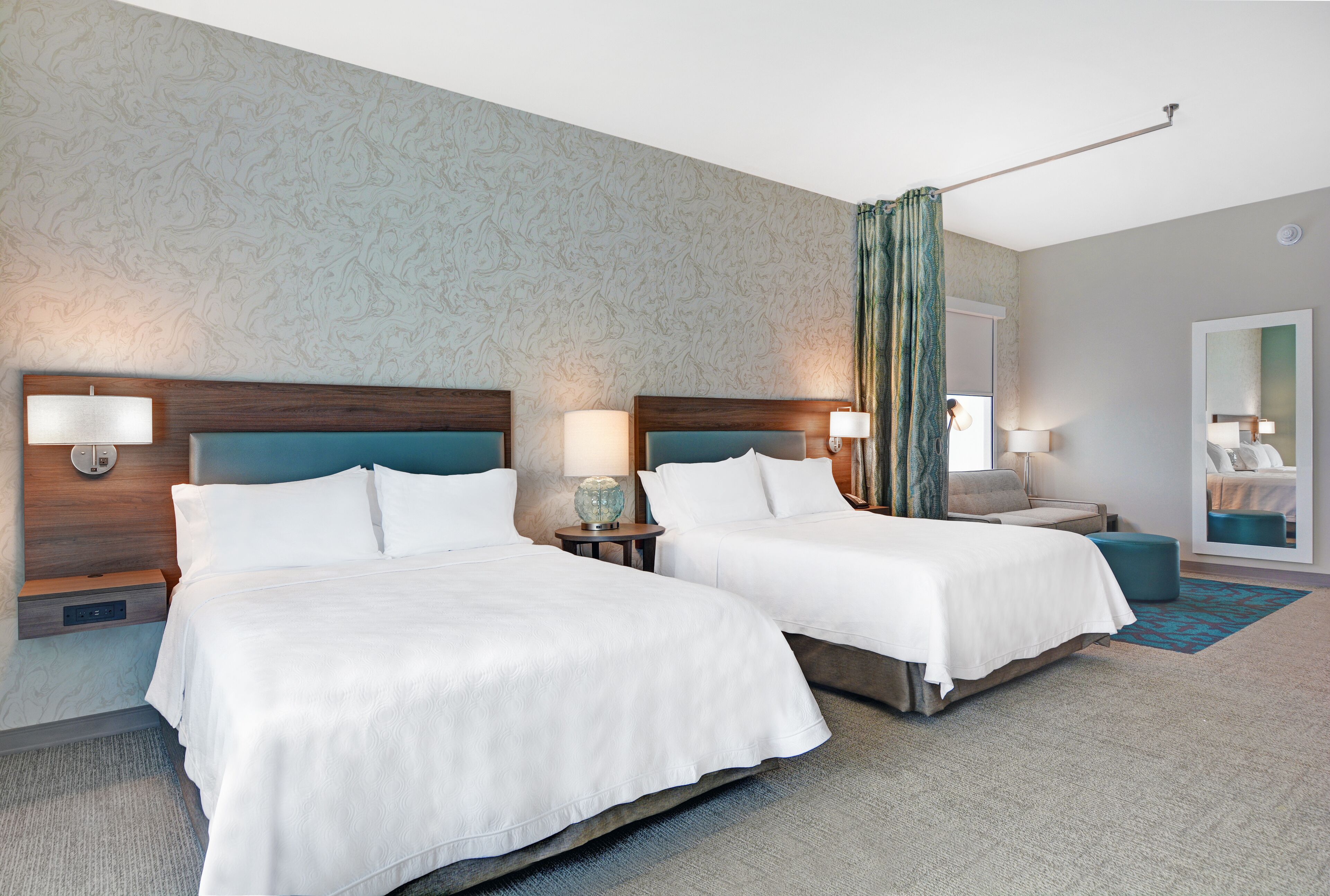Een hotelkamer met twee bedden, een grote spiegel en uitzicht op de stad.