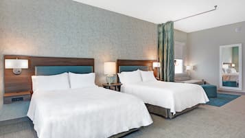 Een hotelkamer met twee bedden, een grote spiegel en uitzicht op de stad.
