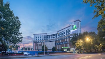 Un hotel Holiday Inn Express con un diseño arquitectónico moderno, situado cerca de una carretera con cielo despejado.
